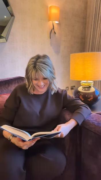 Ruth Langsford smiling while reading a book.