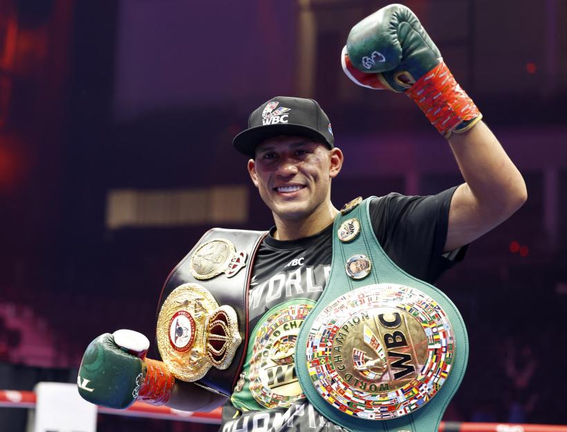 David Benavidez celebrating his victory by holding up his championship belts.