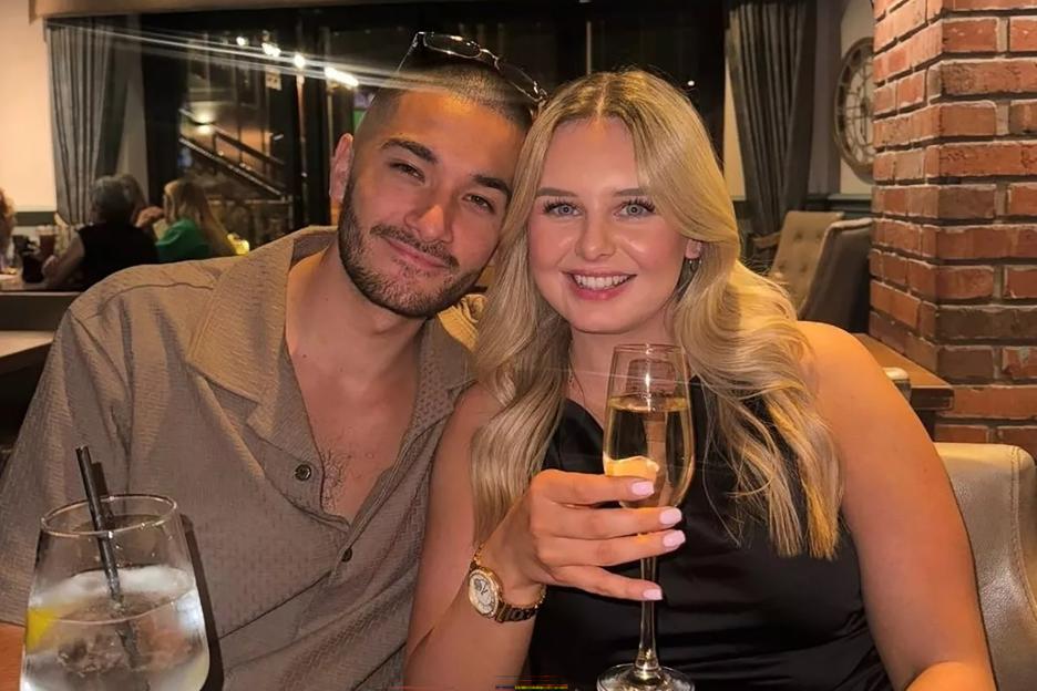 Georgina and Tom Daniels smiling and holding drinks in a restaurant.
