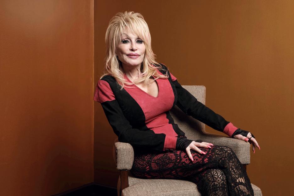 Dolly Parton poses in a red and black outfit.
