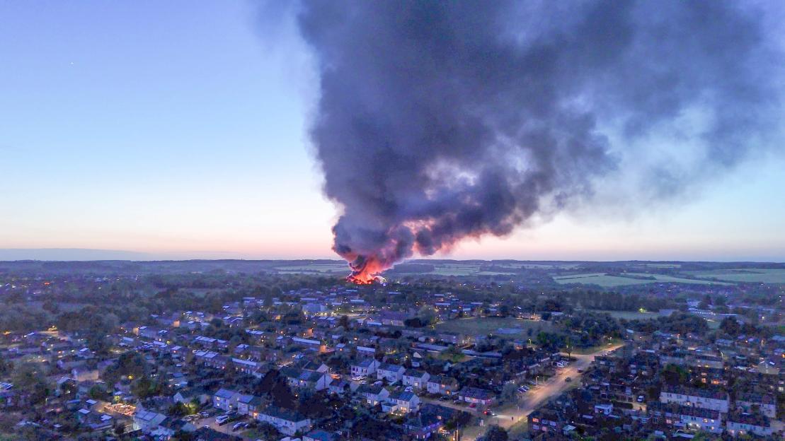 Aerial view of a large fire with dark smoke billowing into the sky over a town in Haverhill, Suffolk.