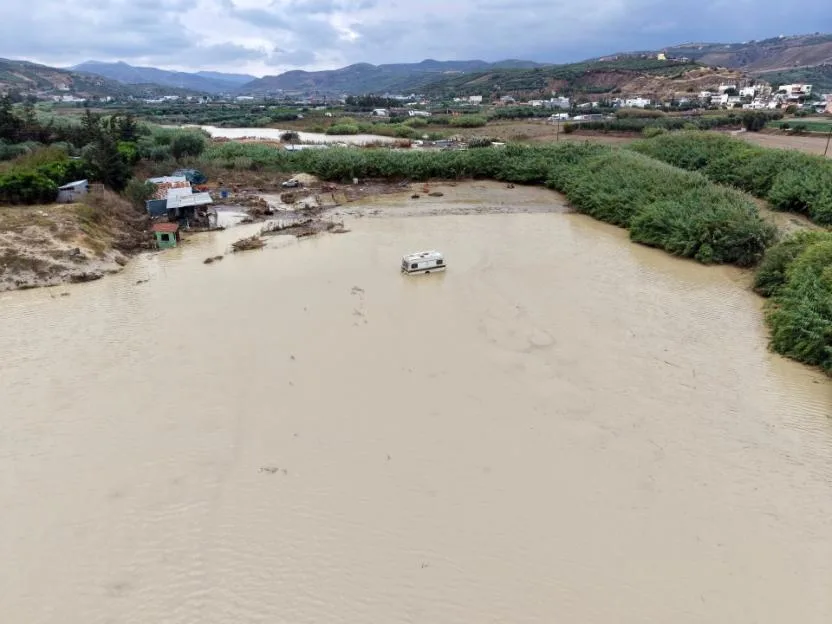 Drone shot of the flooded Drakouliaris River in Heraklion, Crete, Greece, with a caravan stranded in the muddy water.