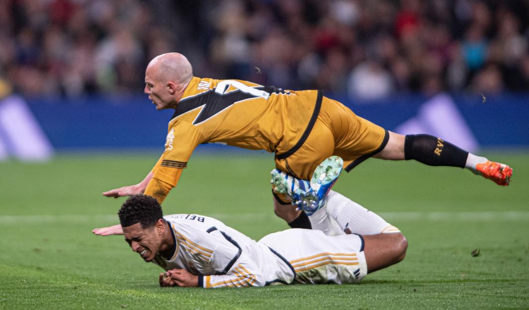 Jude Bellingham slides to stop Isi Palazon during a football match.