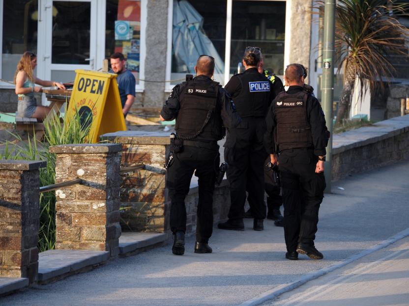 Armed police patrol a street in Polzeath, Cornwall.