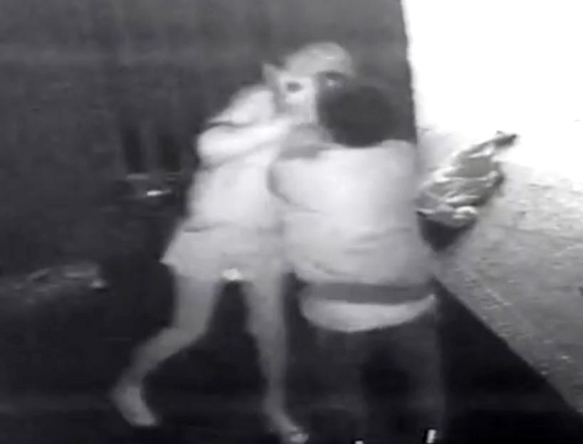 CCTV footage of an assault, showing a person in light clothing being punched by another person in darker clothing.