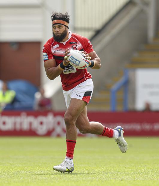 Sitaleki Akauola running with a rugby ball during a match.