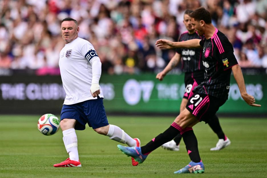 Wayne Rooney playing soccer in a white England jersey with other players in black and pink jerseys.