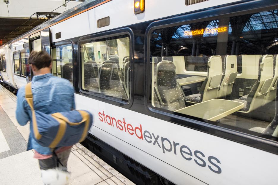a man walking towards a stansted express train