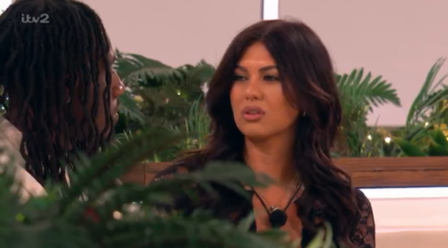 A woman with dark hair talking to a person with dreadlocks.