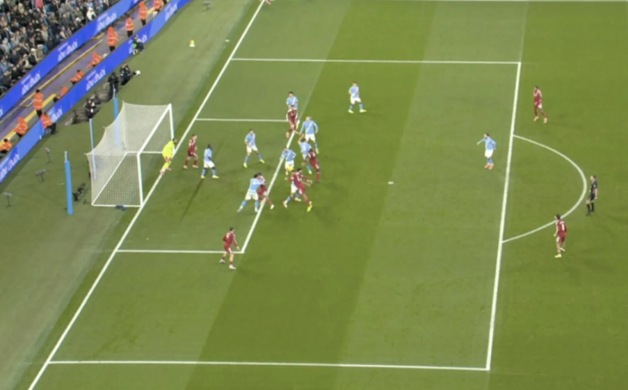An aerial view of a soccer match in progress, with players in red and light blue uniforms on a green field.