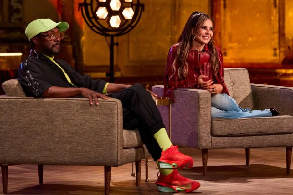 Will.i.am and Cheryl sit in armchairs on the set of The Voice UK.