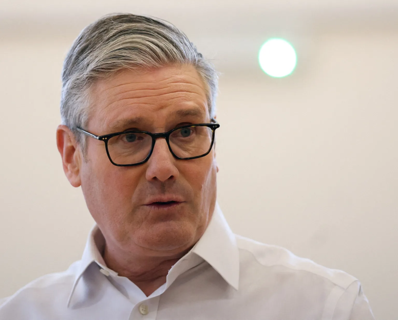 Close-up of a man with gray hair and glasses, wearing a white shirt.