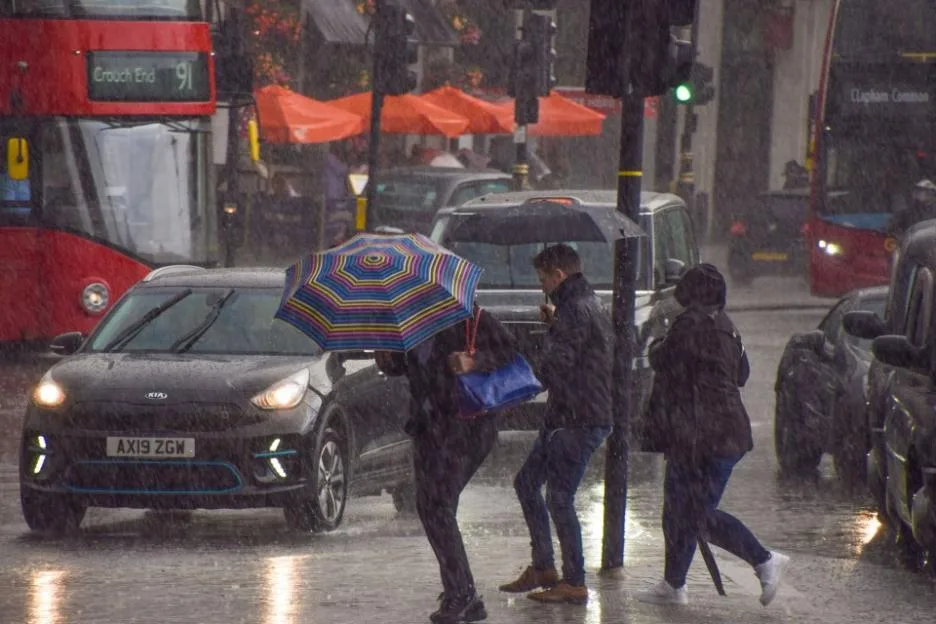People run for cover in Trafalgar Square as torrential rain falls.