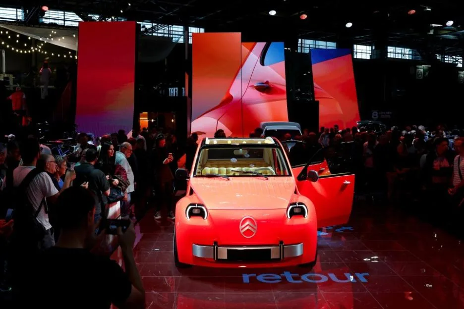Crowds surrounding an orange Citroen car on display at the 2026 Paris Motor Show.