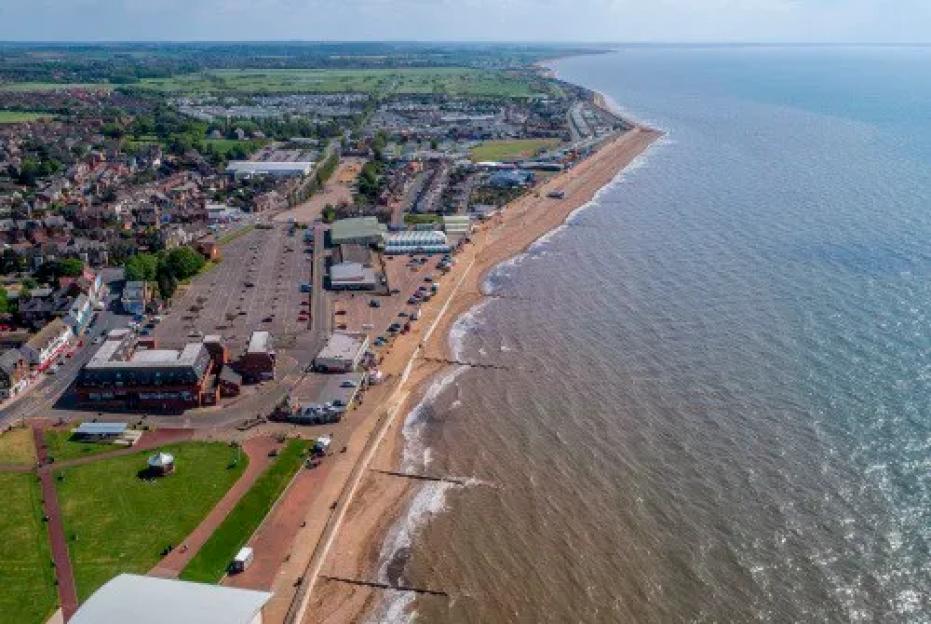 Aerial view of a coastal town with a long sandy beach and the ocean on a clear day.