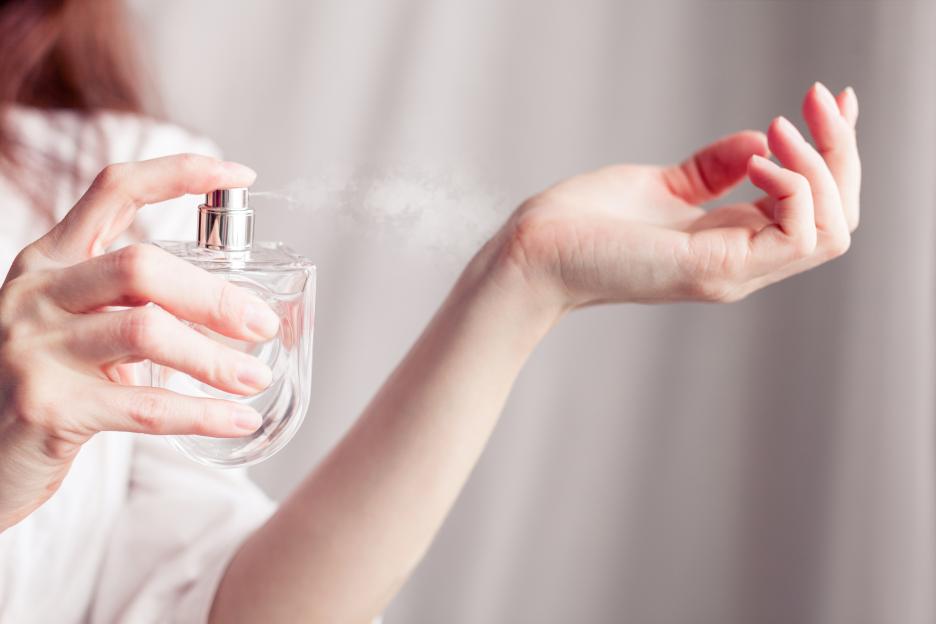 Woman spraying perfume on her wrist.