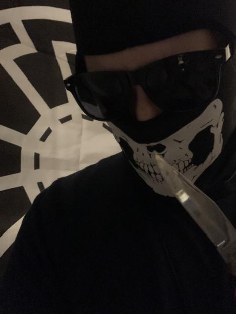 Coleman wearing a skull mask and sunglasses, holding a knife.