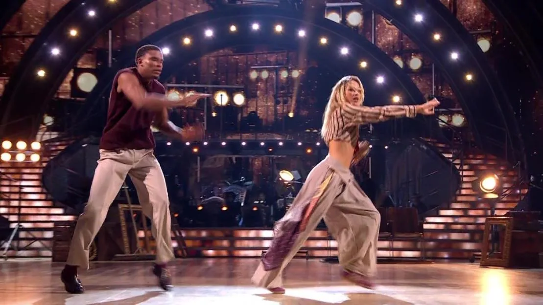 Two dancers on a stage with fireworks and blue stage lights.